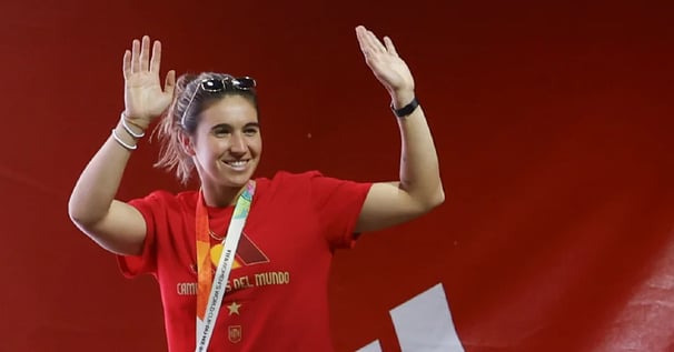 a woman in a red shirt and sunglasses is holding a medal