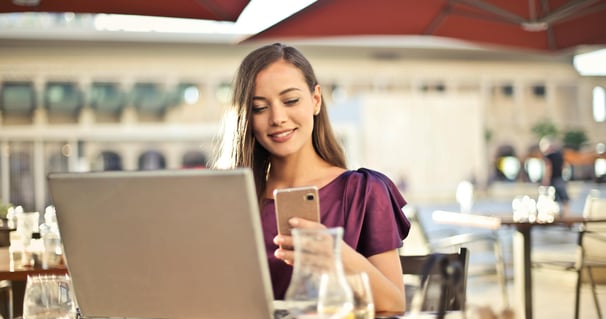 Empreendedora cuidando da gestão do seu negócio, utilizando notebook e celular.