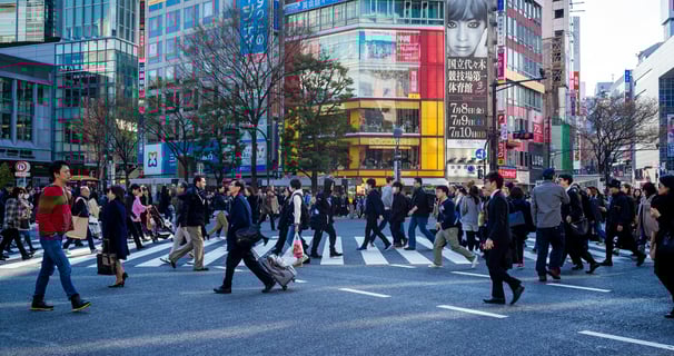 a group of people walking across a busy street