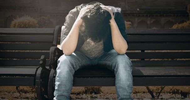 guy sitting on a park bench seemingly scared