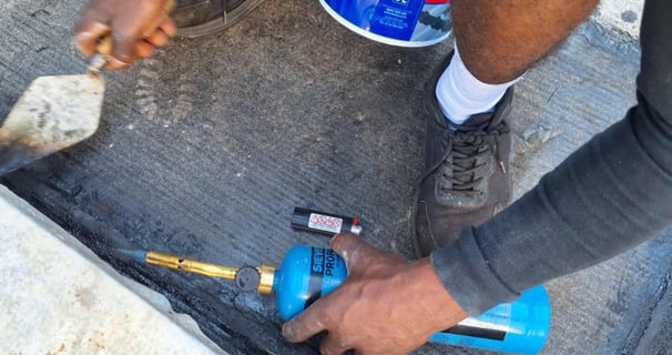 Setting of torch on bitumen with troweling tool, Scottburgh Mall, South Coast, Amanzimtoti