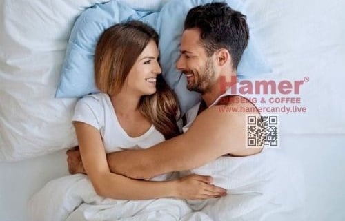 a man and woman are smiling and hugging in bed hamer candy
