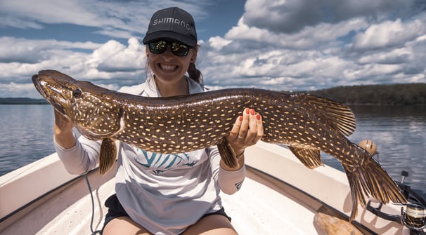 Girl angler proudly posing with her personal best catch, a pike.