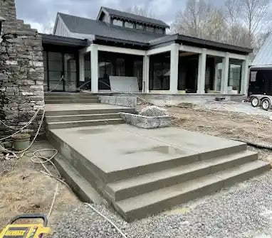 a house with a large concrete patio with steps leading up to a large house