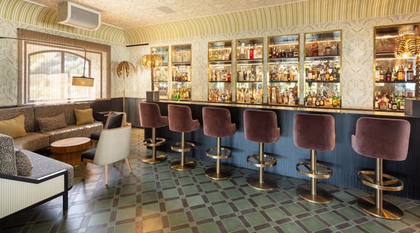 Chic cocktail bar at Villa La Gratitud, featuring plush seating, vintage decor, and a mirrored back.