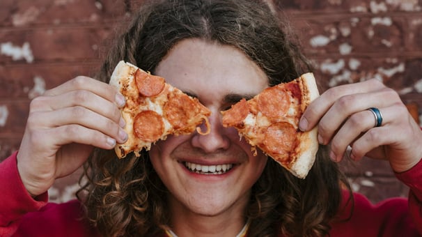 Un adolescent avec des parts de pizza devant ses yeux