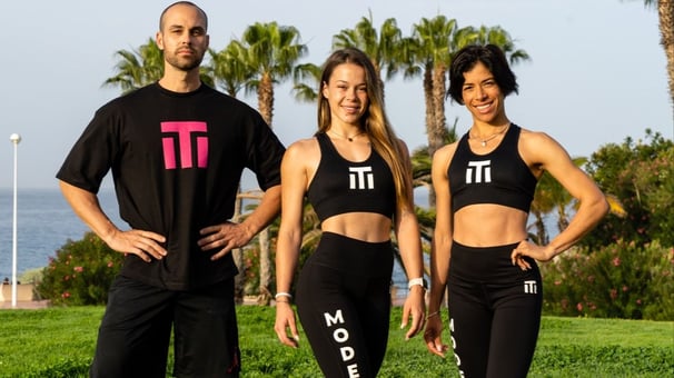 three people standing in front of a body of water