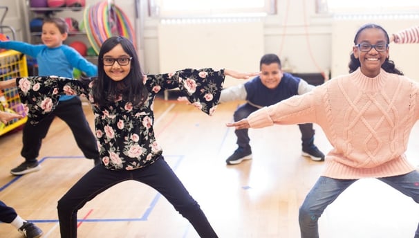 Elementary students to a squat exercise.