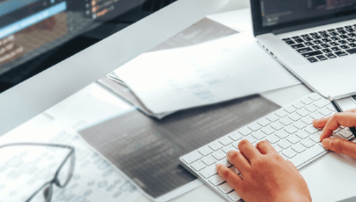 a person sitting at a desk with a laptop and a keyboard