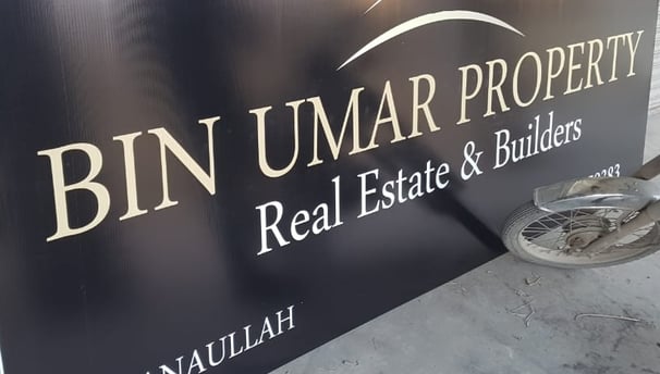 a man is working on a sign for bin umar Property