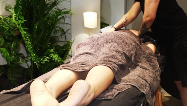 Client receiving a back massage in a calming wellness studio in North West London, promoting relaxat