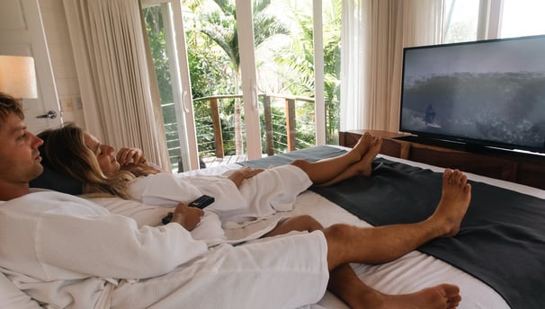 a man and woman sitting on a bed in a hotel room
