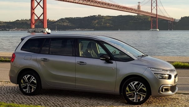 Imagem de um carro em primeiro plano, ao fundo, a Ponte 25 de abril, entre Lisboa e Almada