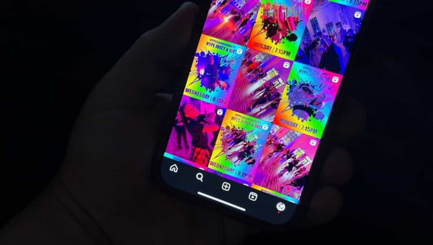 A hand holding a phone with an instagram layout on it showing different posts.
