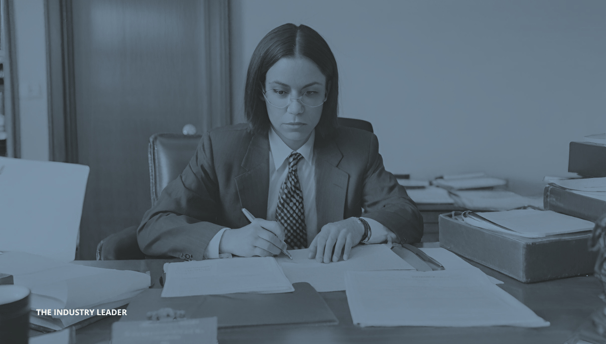 a woman in a suit and tie is sitting at a desk