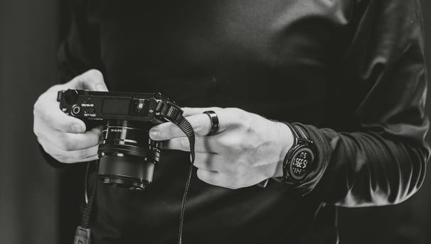 A man holding a camera in a podcast studio.