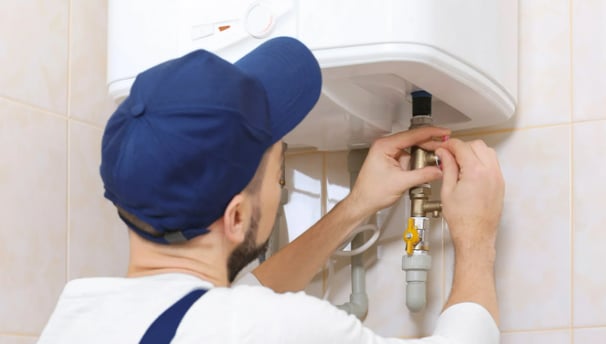 A plumber installing a water heater in a bathroom