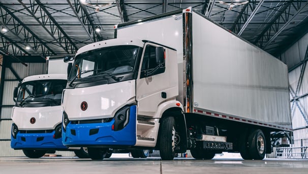 two trucks parked in a warehouse with a large warehouse