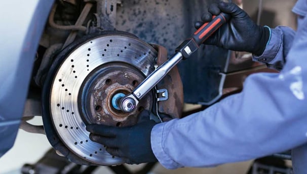 man with a car tool fixing a brake.