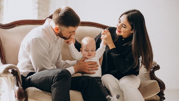 a man and woman sitting on a couch with a baby