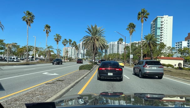 a car driving down a street with palm trees in the background