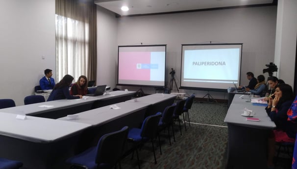 a group of people sitting at a table with a projector