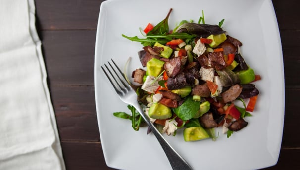 Vista cenital de un plato de carne con verduras, servida en un plato blanco, con tenedor