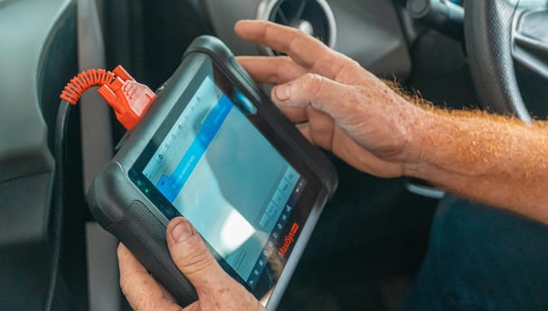 a man holding a car diagnostic computer in his hand
