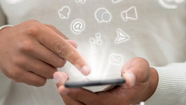 Pessoa segurando um celular, com ícones de redes sociais flutuando