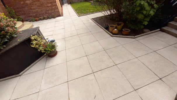 a patio with a white tiled floor and a brick wall