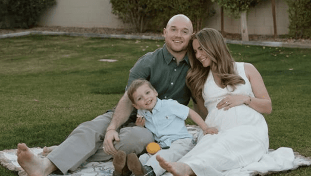 a pregnant woman and her husband are sitting on a blanket