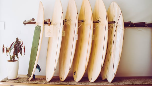 A collection of handmade balsa surfboards neatly displayed on a wooden rack