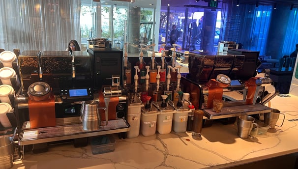 Two Mastrena II super-automatic espresso machines set up at a Starbucks barista station with syrups 