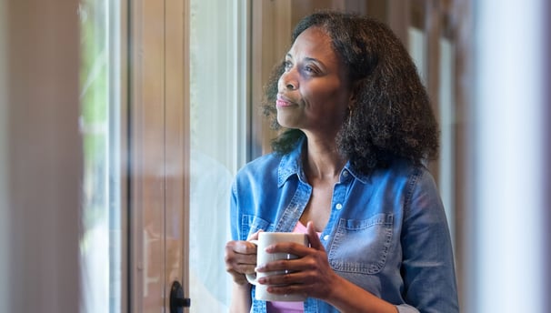 a woman holding a cup of coffee while looking out a window