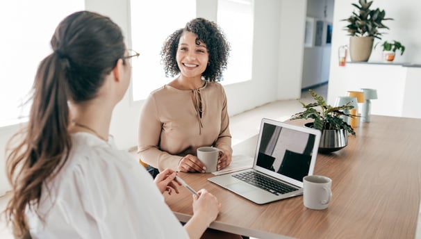 two women sitting at a table in an interview