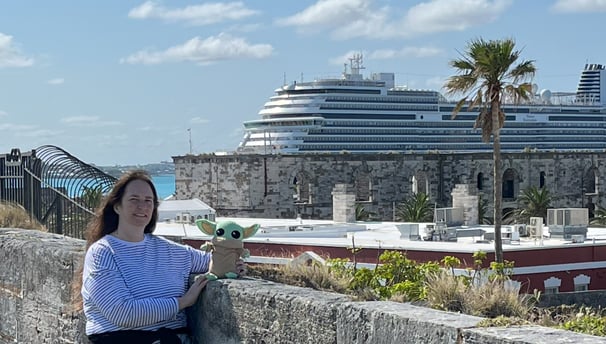 Woman standing against a small wall with Cruise Ship in the background