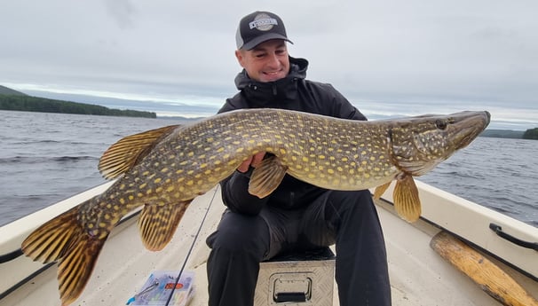 Angler proudly posing with his personal best catch, a pike.