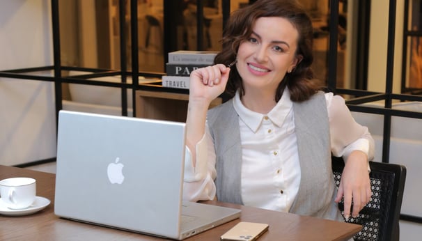 Woman in her late 30s at a desk with laptop, phone and pen, representing a soulful purpose mentor