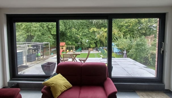 big panorama window, a couch in a living room with a view of the backyard
