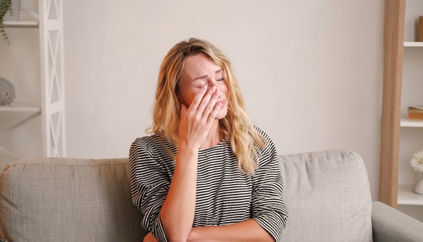 a woman sitting on a couch with her hands on her face