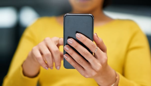 a woman in a yellow shirt is holding a cell phone