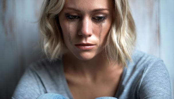 a woman with blonde hair and a gray shirt crying