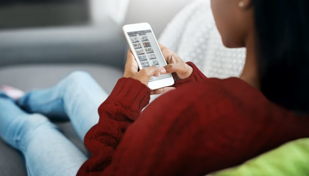 a woman sitting on a couch holding a cell phone