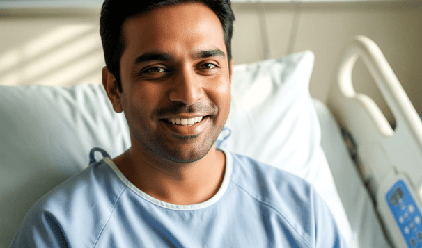 A man in a hospital bed wearing a blue gown.