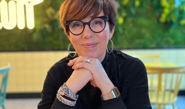 Portrait de Laurence Boukraa. Elle sourit les coudes sont posés sur une table
