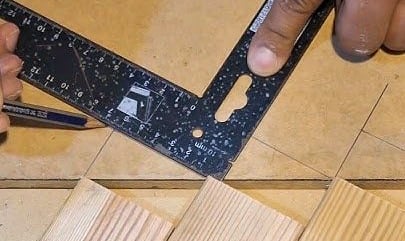 Contractor using a speed square to mark precise cuts on wood slats for custom wall panel installation