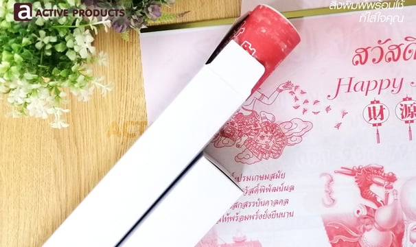 กล่องสีขาวเทาเปิดฝาพร้อมใส่ปฎิทินจีน วางบนกองปฎิทินบนโต๊ะไม้สีอ่อน พร้อมต้นไม้