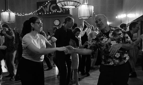 a woman in a floral shirt dancing with a man in a suit