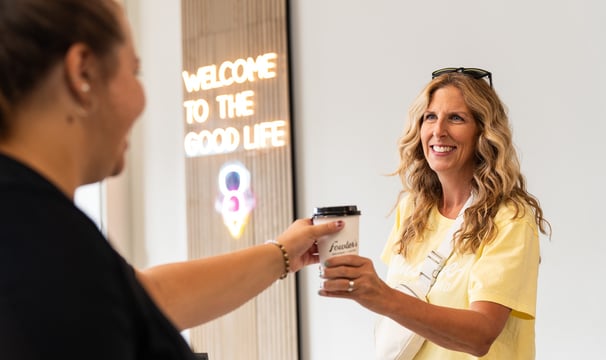 a woman is handing a cup of coffee to a customer