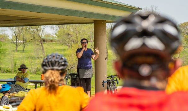 Mayor Barbara Buffaloe speaking into a microphone before a group of people wearing bike helmets